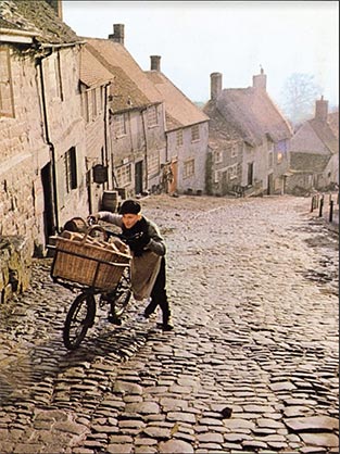 A still from the iconic Hovis advert of the bakery delivery boy pushing his bike up a steep hill.