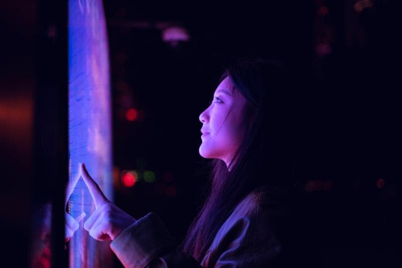 Young asian woman using touch screen in financial district at night